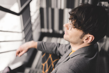 Obraz premium selective focus of dreamy young man in glasses sitting on stairs
