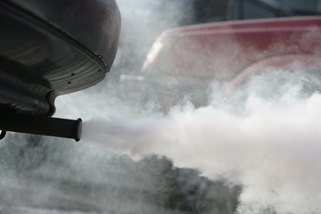 Auspuff und herausstroemende Abgase, helle Rauchwolken .