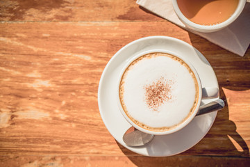 Hot coffee and hot tea place on the wooden table in early morning with copyspace, white cup and silver spoon.
