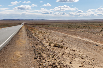 asphalt road Sainshand Zamiin-Uud in Mongolia, desert landscape Gobi Desert