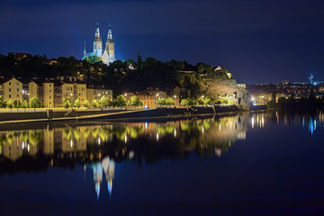 Fototapeta na wymiar Prague, Czech Republic. Basilica of St. Peter and St. Paul on the Vysehrad Hill, reflecting in the water of Vltava river in night.
