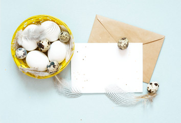 Blank greeting card, kraft envelope. Easter composition with easter eggs and feathers on blue background. Image