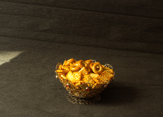Wicker vase of silver filled with biscuits stands on a black background
