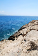 Large stones washed by sea waves with white foam against a blue sky, Cape Fourny, Rhodes Island, Greece