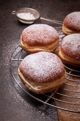 Yummy and fresh donuts on cooling grate on dark table