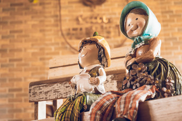 Lovely vintage happy woman and boy doll in sitting position and wear costume country closeup on coffee wall blur background. Abstract of lovely family and warm love.
