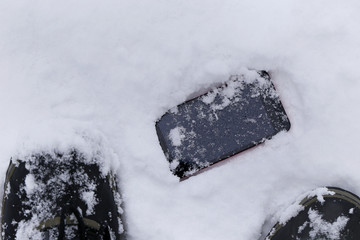 足元の雪の上に落としたスマートフォン