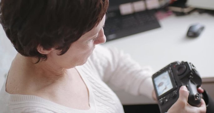 Rear view of adult european woman looks at the photos on the camera.