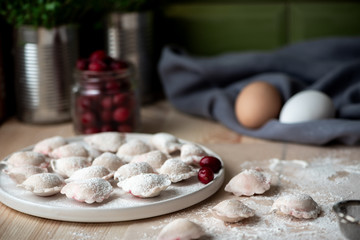 Uncooked dumplings with berry on the kitchen table.