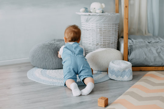 The kid plays in a beautiful children's room. The child crawls on the nursery. Little boy playing