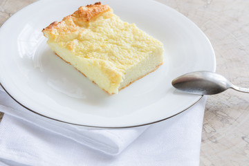 Piece of curd casserole on white plate on wooden cut. 