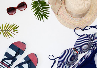 Flat lay summer beach holiday accesorries on white background with palm leaf, camera, straw hatand and sunglasses.Space for text. Travel and beach vacation, top view.Overhead view of woman's swimwear.