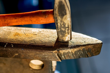 Hammer on a metal anvil in a workshop. Close-up of metalworking tools.
