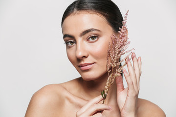 Healthy attractive brunette woman standing isolated holding flower plant near her face