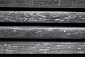 Close up of texture of grey weathered wood planks with gaps.