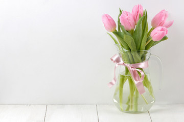 Bouquet of beautiful pink tulips flowers in a vase on a white wooden table. Spring. holidays. free space