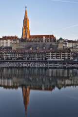 The Bern Minster (Münster) in the old town of Bern, capital city of Switzerland. Seen from across the river (Aare) with reflection.