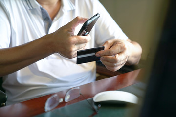Obraz na płótnie Canvas Online payment : Man holding a smart phone and credit card ready to make a purchase