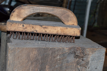 An old dirty and grungy wire brush on a block of wood inside the blacksmith shop in Missouri. Bokeh effect.