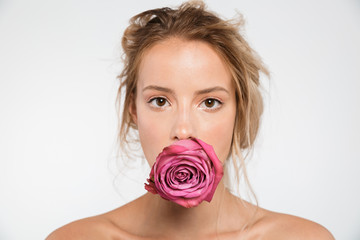 Beautiful young naked woman posing isolated over white wall background with flower.