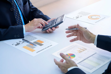 Two businessmen are deeply reviewing a financial reports for a return on investment or investment...