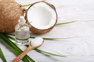Coconut shell pieces and palm leaves on white wooden table