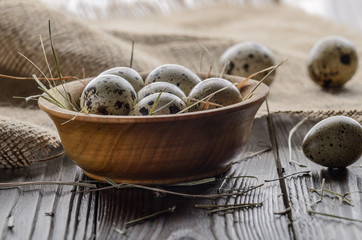 Fresh organic quail eggs in wooden bowl on rustic kitchen table. Space for text