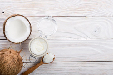 Flat lay background of coconut, coconut shell, hard oil in airtight glass jar on white wooden table
