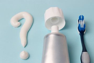 Question mark from toothpaste and toothbrush on blue background
