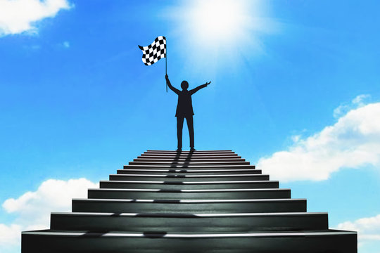 The silhouette of a businessman holding a chess flag standing on the stairs. The concept of success - image
