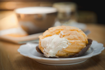 Close up Chousx cream or Choux pastry with a cup of hot chocolate and blur background on wooden table.