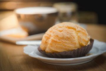 Close up Chousx cream or Choux pastry with a cup of hot chocolate and blur background on wooden table.