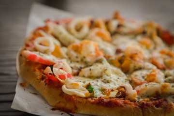  Baked small size homemade supreme seafood pizza on wooden table, close up 