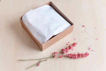 Brown craft paper gift box with dried flowers on wooden table. Selective focus.