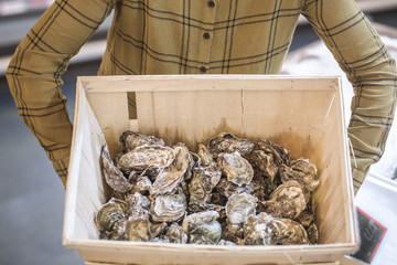Woman in the supermarket with oysters. Beautiful young woman is holding a large box of oysters