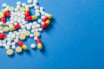 Heap of various pills isolated on blue background.