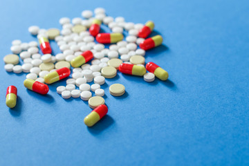Heap of various pills isolated on blue background.