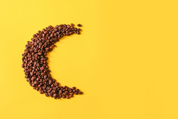 Roasted coffee grains lying in the shape of the moon from