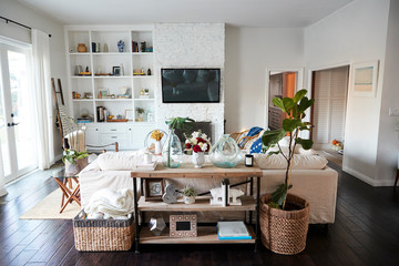 A family living room with white walls and dark wood floorboards seen in daylight, from behind the...