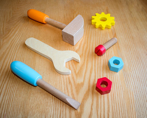 set of colored wooden toy tools on a wooden background