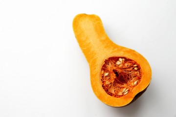 Orange pumpkin is cut and is on a white background near the pumpkin visible seeds and pulp