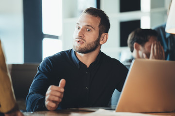 Surprised man talking to woman manager in the office and using laptop