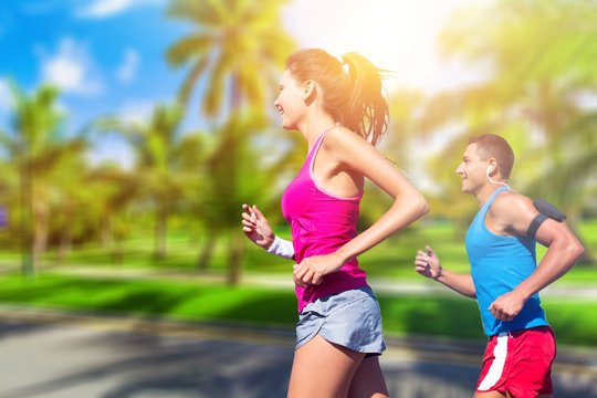 Fitness, sport, friendship and lifestyle concept - smiling couple  running together