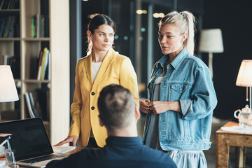 Two women employees and chief manager discussing new work strategy in the office