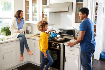 Mixed race parents and their daughter spending time together preparing food in the kitchen