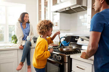 Close up of young family spending time together while preparing food in their kitchen, selective...
