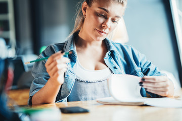 Handsome woman employee sitting at the table and working with notepad