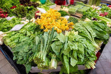 Fototapeta na wymiar Fresh organic green vegetables at farmers market. Pumpkin flowers, lettuce leaves.