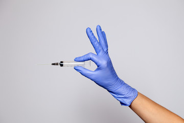 Closeup doctor hand in rubber latex medical purple glove hold transparent syringe with sharp...
