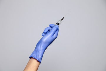 Closeup hand in rubber latex medicine purple glove holding transparent syringe with a sharp needle....